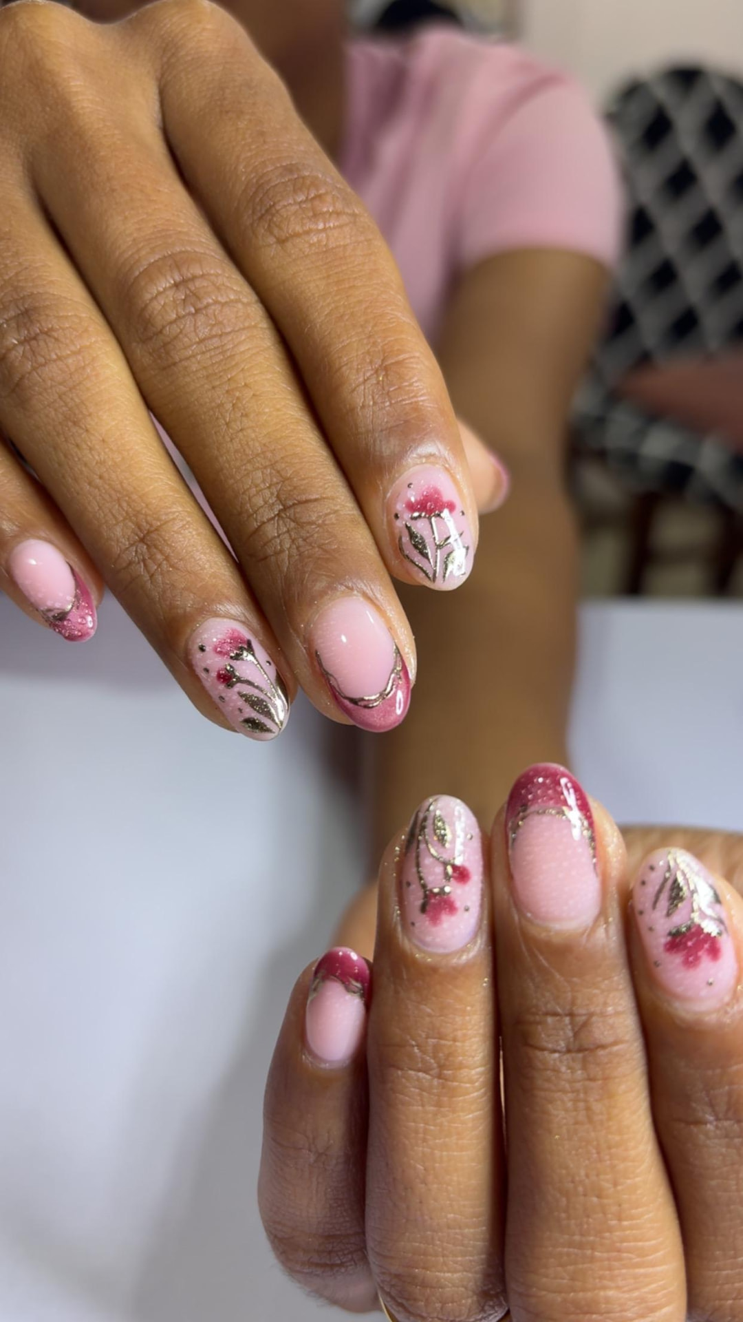 Soft pink nails with gold leaf line-art and berry accents