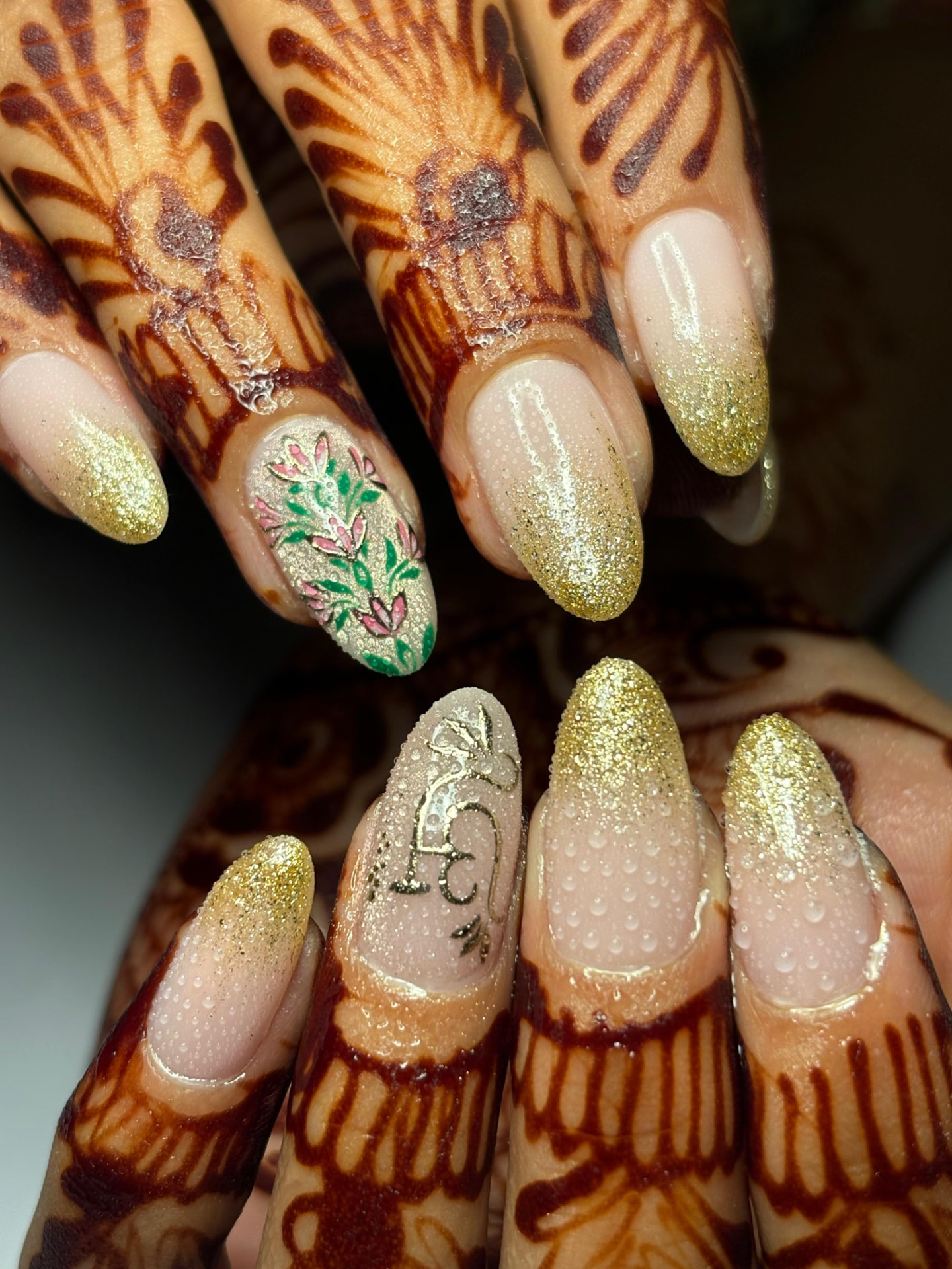 Gold glitter ombre nails with painted floral accent for a mehendi look
