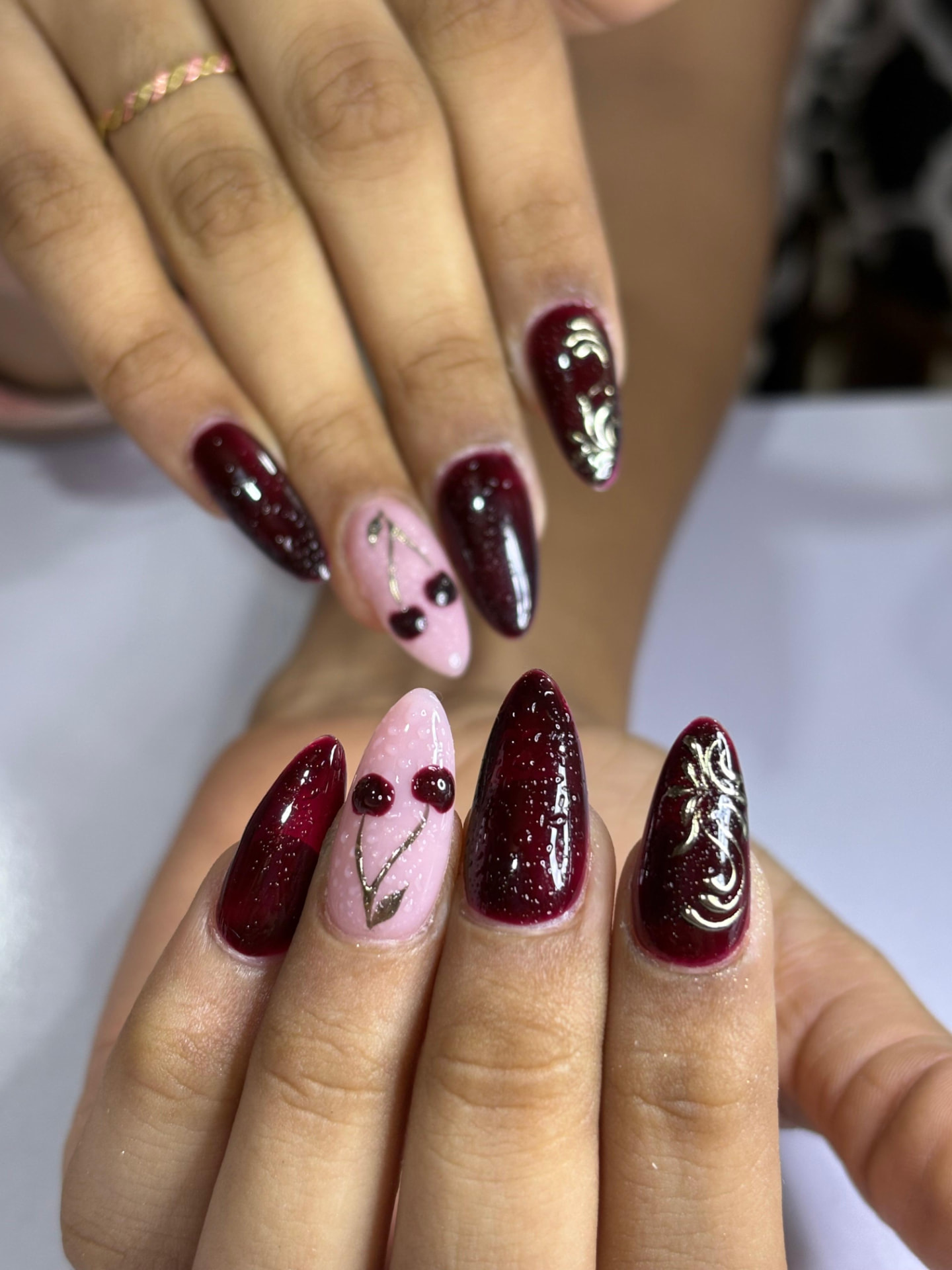 Deep wine almond nails with gold filigree and 3D cherry accent nail