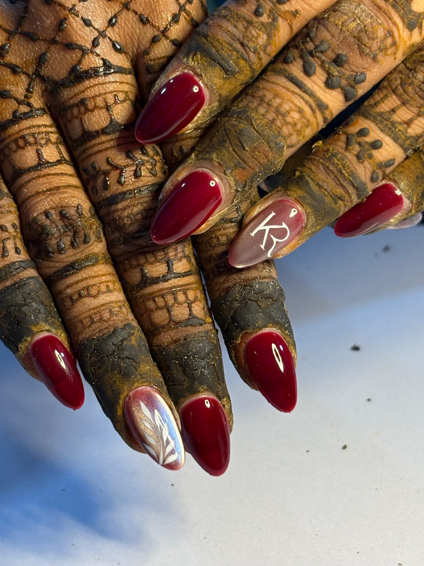 Glossy deep red almond nails with initials accent nail